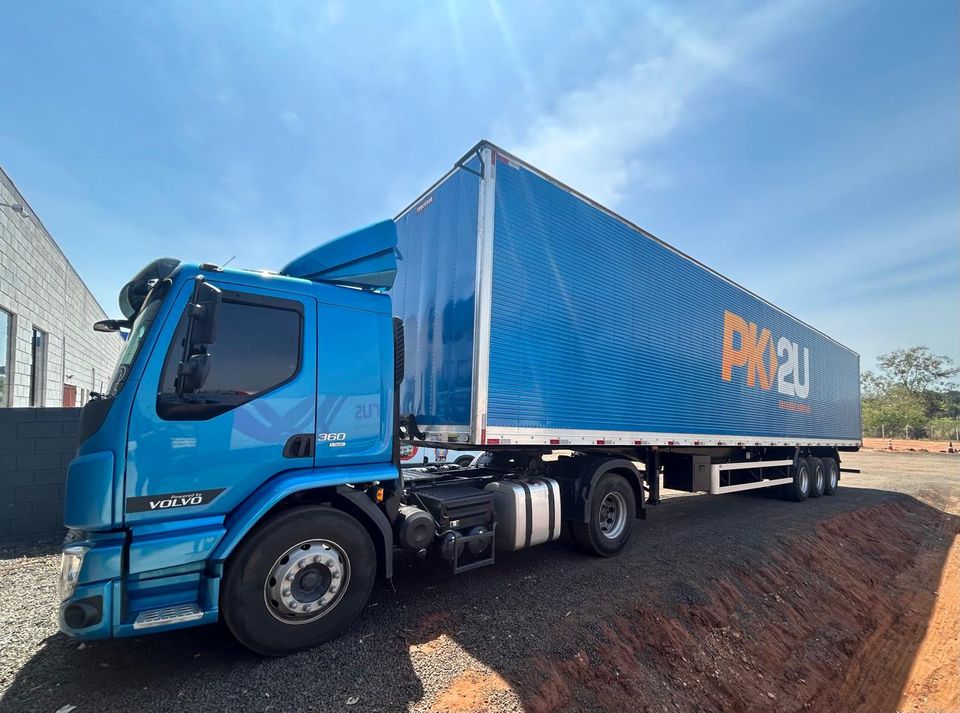 Cavalo mecânico Volvo azul atrelado a carreta baú com a marca PK2U